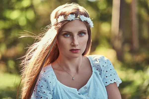 Una hermosa mujer en un vestido blanco y corona blanca en la cabeza posando en un bosque verde de otoño . — Foto de Stock