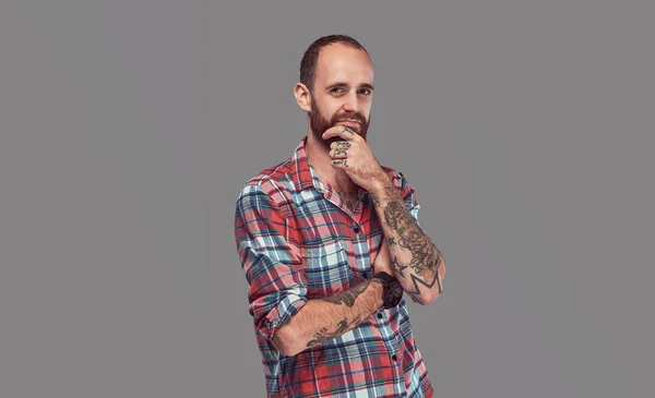 Portret van een knappe getatoeëerd stijlvolle hipster met een goed getrimd baard in een flanellen shirt, poseren in een studio. — Stockfoto