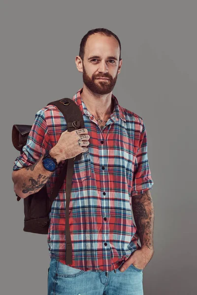 Retrato de un guapo viajero tatuado en una camisa de franela con una mochila, de pie en un estudio . —  Fotos de Stock