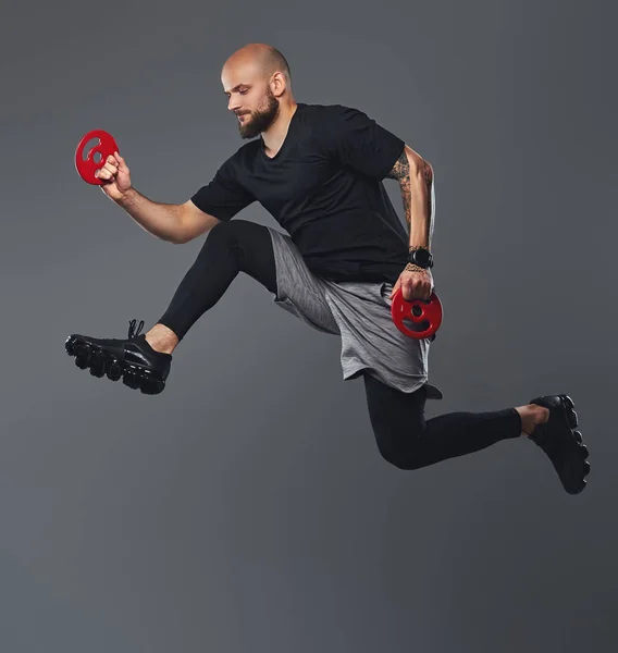 Handsome bearded athlete in sportswear jumping in a studio.