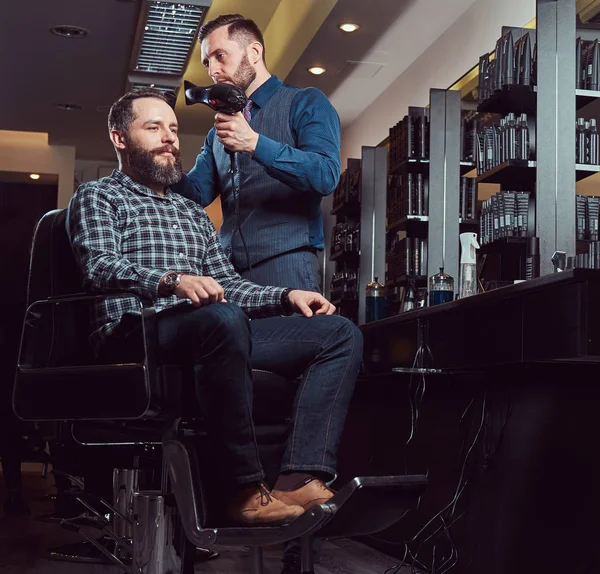 Професійний перукар, що працює з клієнтом у перукарні, використовує фен . — стокове фото