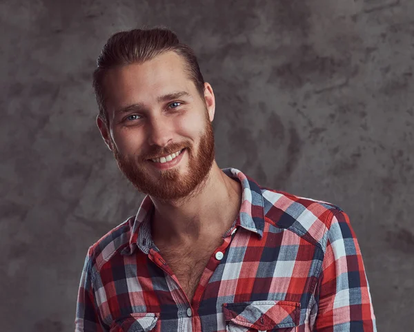 Young handsome redhead model man in a flannel shirt on a gray background.