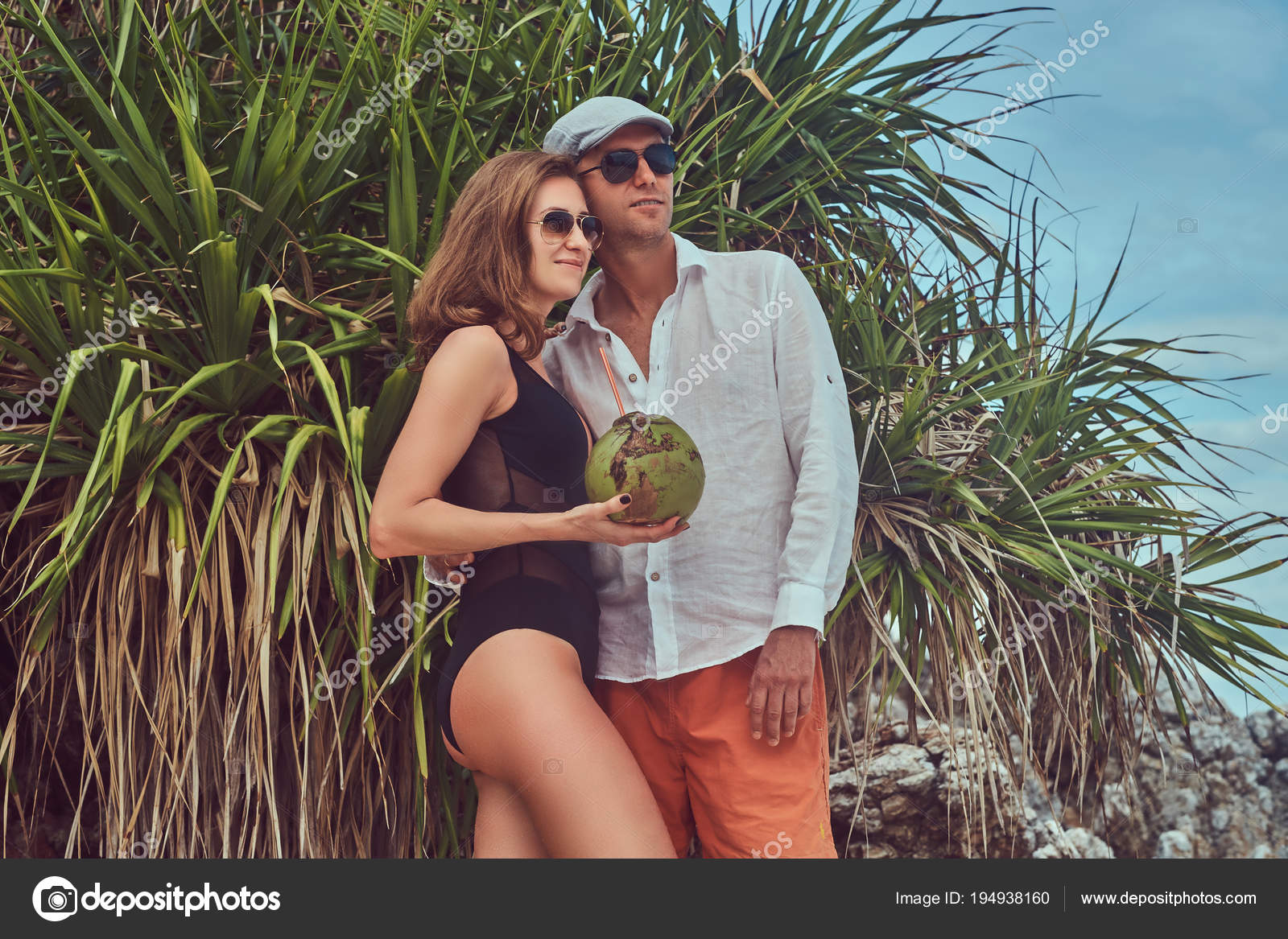 Attractive Couple Holds Coconut With A Tube Posing On A Beach Near Palm Bush Enjoys A Vacation On A Beautiful Island Stock Photo Image By C Fxquadro 194938160
