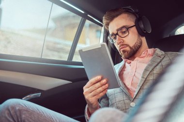 Bir gri takım elbise ve pembe gömlek, başarılı şık genç işadamı bir arka koltukta bir lüks Araba sürme.