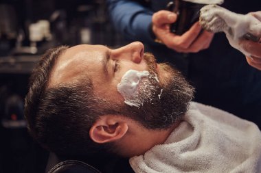 Usta Kuaför yüz tıraş için hazırlar ve yüzü bir kuaför salonu olarak köpük ile smear.