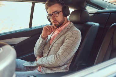 Bir gri takım elbise ve pembe gömlek, başarılı şık genç işadamı bir arka koltukta bir lüks Araba sürme.