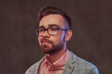 Yakın çekim portre bir emin şık bir stüdyoda poz adamla saç modeli ve gözlük bir gri takım elbise ve pembe gömlek, sakallı.