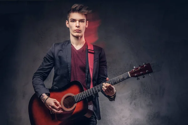 Stylowe młody muzyk z stylowe włosów w eleganckie ubrania, gra na gitarze akustycznej. — Zdjęcie stockowe