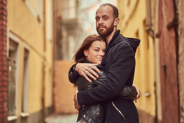 Szakállas férfi és barna lány a csókolózás, a háttérben a régi európai utca. — Stock Fotó