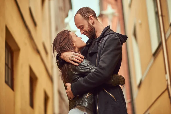 Bearded man and brunette girl kissing, on the background of the old European street. — Stock Photo, Image