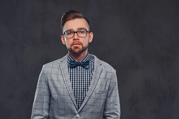 Впевнений стильний бородатий чоловік з зачіскою і окулярами в елегантному ретро-сірому костюмі і краватці, позує в студії . — стокове фото