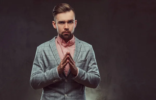 Pensativo hombre barbudo con estilo con peinado y gafas en un traje gris y camisa rosa, posando en un estudio . —  Fotos de Stock