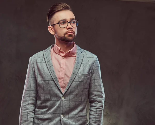 Porträt eines selbstbewussten bärtigen Mannes mit Frisur und Brille im grauen Anzug und rosa Hemd, der in einem Studio posiert. — Stockfoto