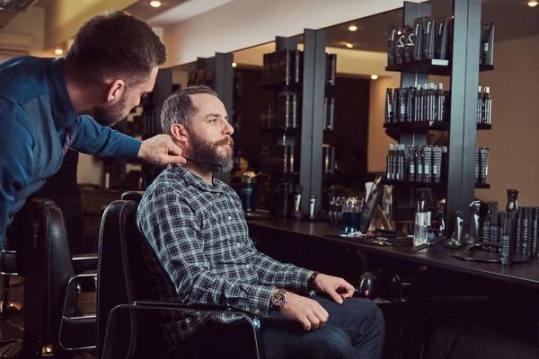 Barbiere professionista che lavora con un cliente in un salone di parrucchiere . — Foto Stock