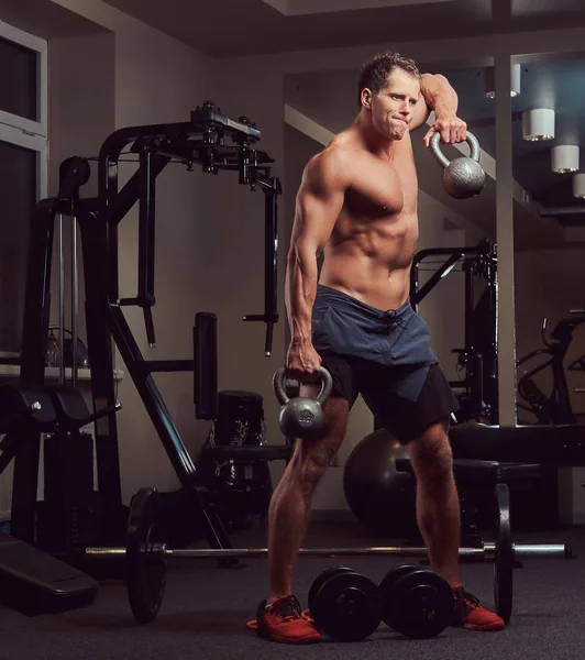 Yakışıklı kaslı gömleksiz vücut geliştirmeci erkek spor salonunda bir dumbbell ile yapıyor. — Stok fotoğraf