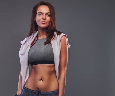 İnce fitness esmer kadın bir stüdyoda poz gri bir spor giyim.