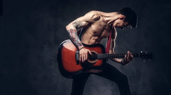 Schöner hemdloser junger Musiker, der beim Springen Gitarre spielt. — Stockfoto