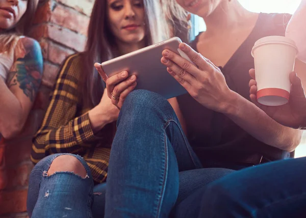 Group of female friends in casual clothes discussing while looking something on a digital tablet in a room with loft interior. — Stock Photo, Image