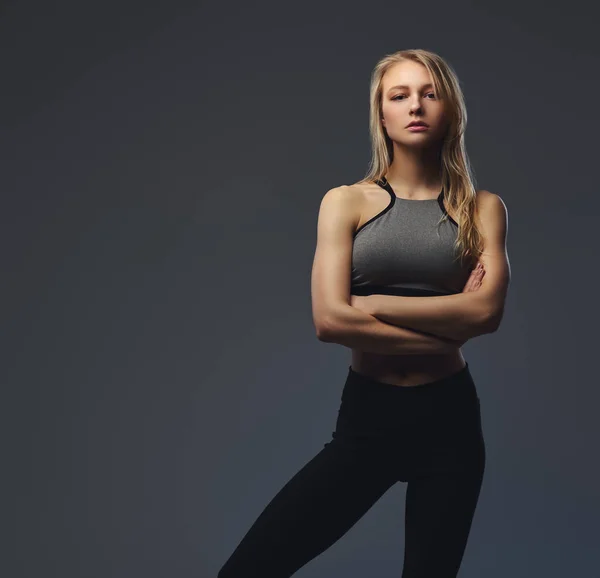Sexy schlanke blonde Mädchen in Sportbekleidung posiert in einem Studio. — Stockfoto