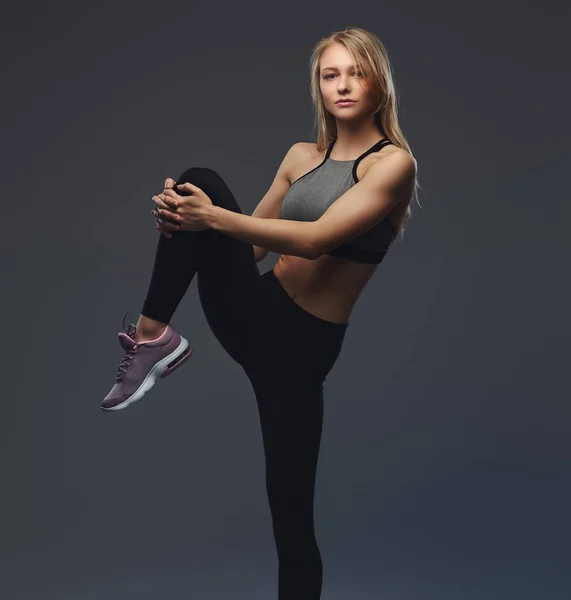 Vacker blond flicka sträcker benen före träning. — Stockfoto