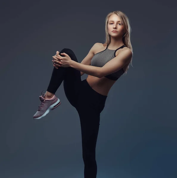 Vacker blond flicka sträcker benen före träning. — Stockfoto