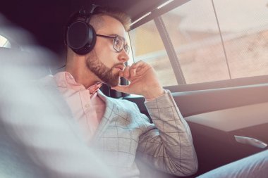 Bir gri takım elbise ve pembe gömlek, başarılı şık genç işadamı bir arka koltukta bir lüks Araba sürme.