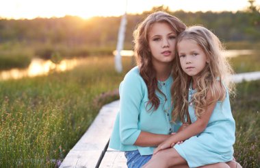 Kız açık havada günbatımına ahşap yol alan üzerinde otururken rahatlatıcı.