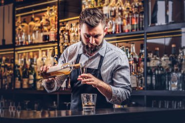Bir gömlek ve önlük şık acımasız barmen, bir kokteyl bar counter arka plan yapar.