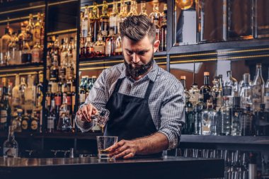 Bir gömlek ve önlük şık acımasız barmen, bir kokteyl bar counter arka plan yapar.