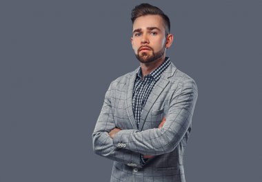 Sakallı yakışıklı zarif bir gri ceketli saç modeli ile ile poz silah bir kameraya bakarak bir stüdyoda geçti.