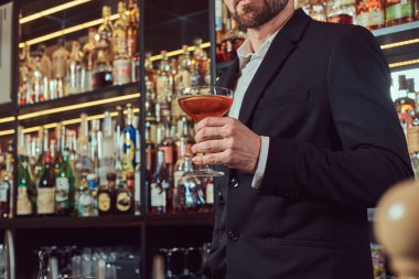 Yakışıklı şık erkek bir bardak bar counter arka plan, özel alkol ayakta tutan.