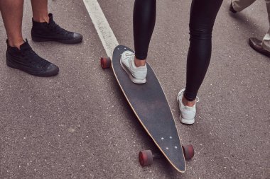 Eğlence ve spor kavram - genç çift ayak bir sokakta bir longboard ile yakın çekim.
