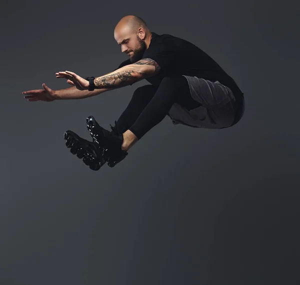 Handsome bearded athlete in sportswear jumping in a studio.