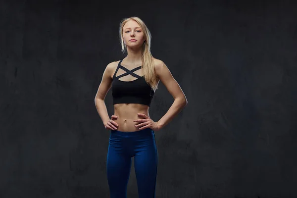 Sexy schlanke blonde Mädchen in Sportbekleidung posiert in einem Studio. — Stockfoto