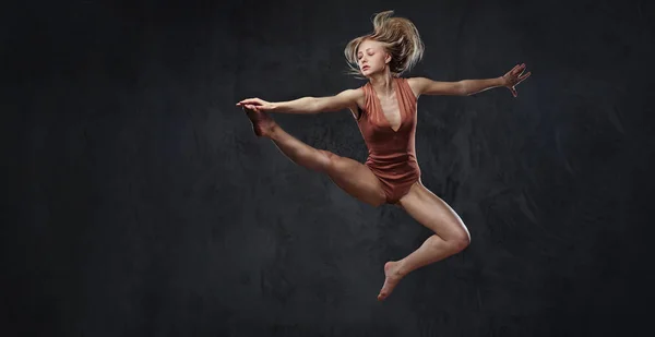Молода витончена балерина танцює і стрибає в студії. Ізольовані на темному тлі . — стокове фото