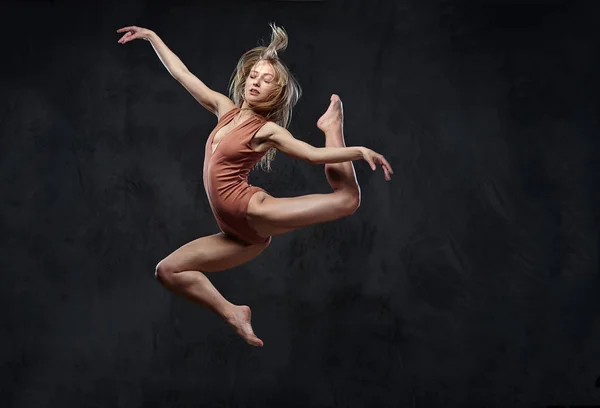 Joven bailarina elegante baila y salta en un estudio. Aislado sobre un fondo oscuro . — Foto de Stock