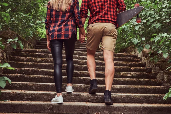 Молодая пара хипстеров, прогулка в парке, держась за руки, поднимаясь по лестнице . — стоковое фото