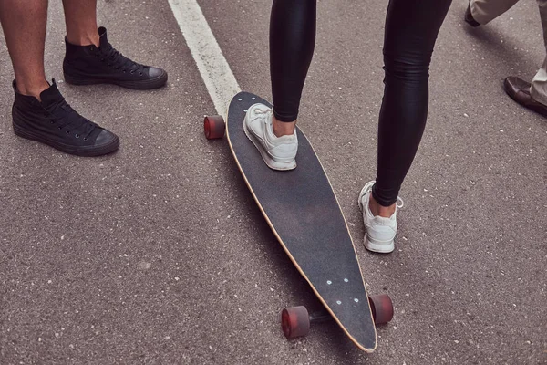 Eğlence ve spor kavram - genç çift ayak bir sokakta bir longboard ile yakın çekim. — Stok fotoğraf