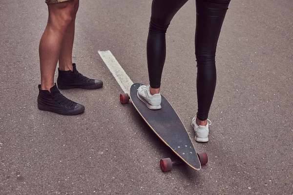 Leisure and sports concept - close-up of teenage couple feet with a longboard on a street. — Stock Photo, Image