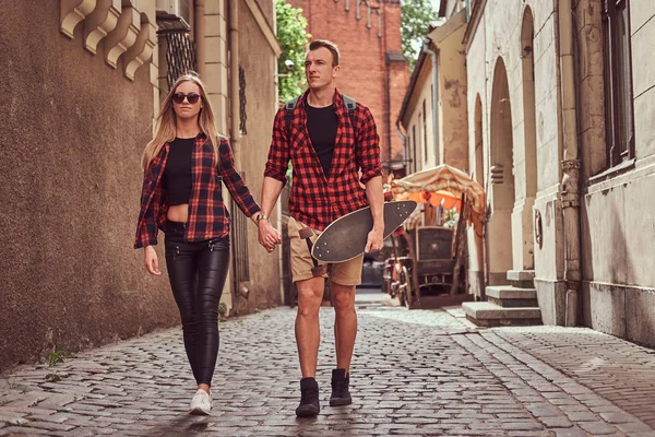 Pár mladých bokovky, hezký bruslař a jeho přítelkyně, procházky kolem starých úzkých ulicích Evropy. — Stock fotografie