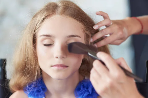 Stylist gör sminket för en vacker liten flicka modell. — Stockfoto