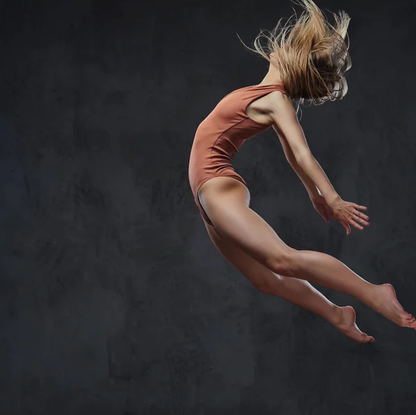 Joven bailarina elegante baila y salta en un estudio. Aislado sobre un fondo oscuro . — Foto de Stock