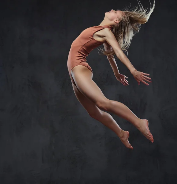 Joven bailarina elegante baila y salta en un estudio. Aislado sobre un fondo oscuro . — Foto de Stock