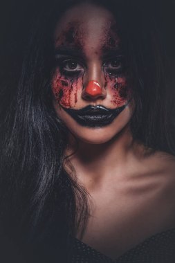 Karanlık fotoğraf stüdyosundaki şeytani palyaço portresi.
