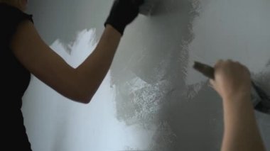 Çocuk, annesine duvarı boyaması için yardım ediyor.