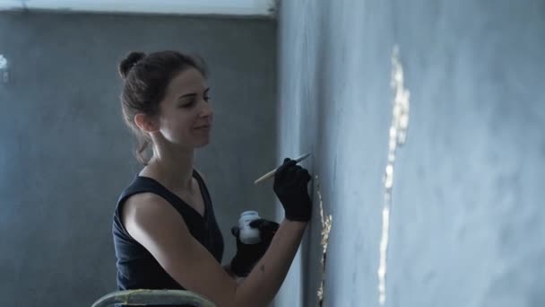 Η γυναίκα ζωγραφίζει στον γκρίζο τοίχο — Αρχείο Βίντεο