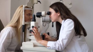 Göz doktoru hastaların gözlerini kontrol ediyor.