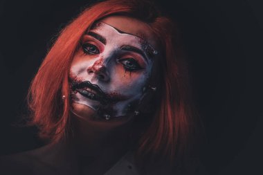 Yüzünde korkunç bebek resmi olan kızıl bir kızın portresi.
