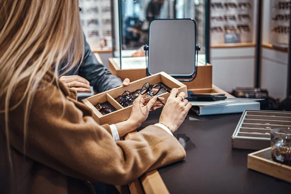 Senhora está escolhendo novos óculos na loja — Fotografia de Stock