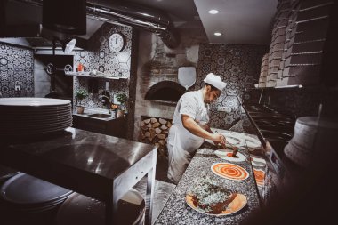 Şef restoranın mutfağında pizza yapıyor.